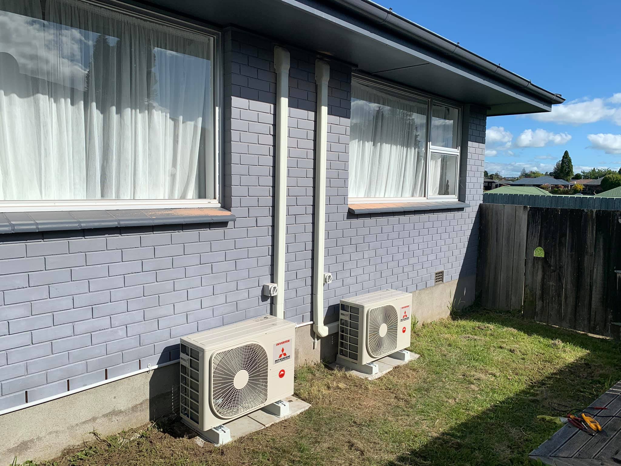 Two Mitsubishi Electric outdoor heat pump units installed beside a home