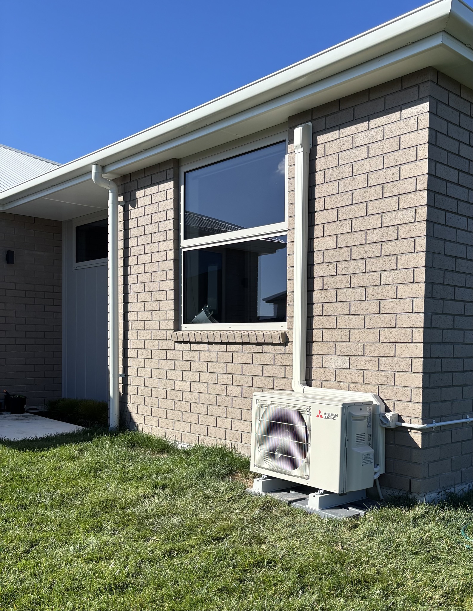 Mitsubishi Electric outdoor heat pump installed neatly beside a brick home