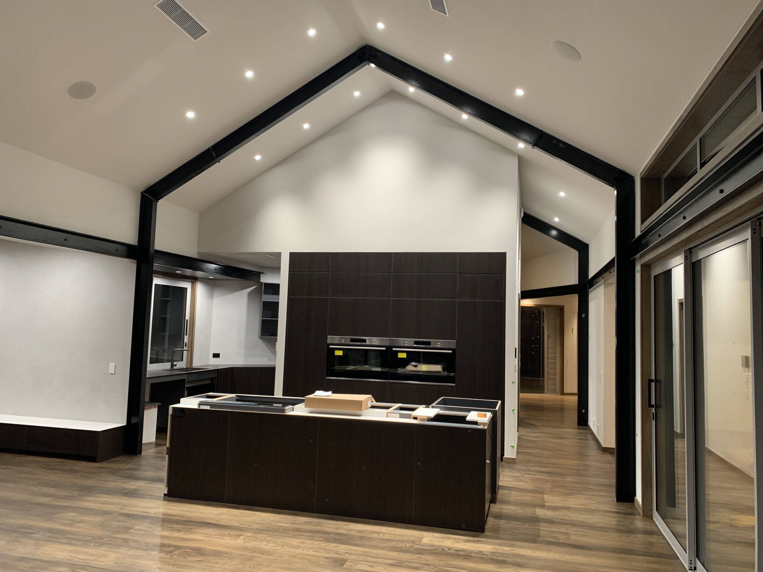 High-spec kitchen illuminated using narrow 20° beam LED downlights beneath a 5 metre raked ceiling
